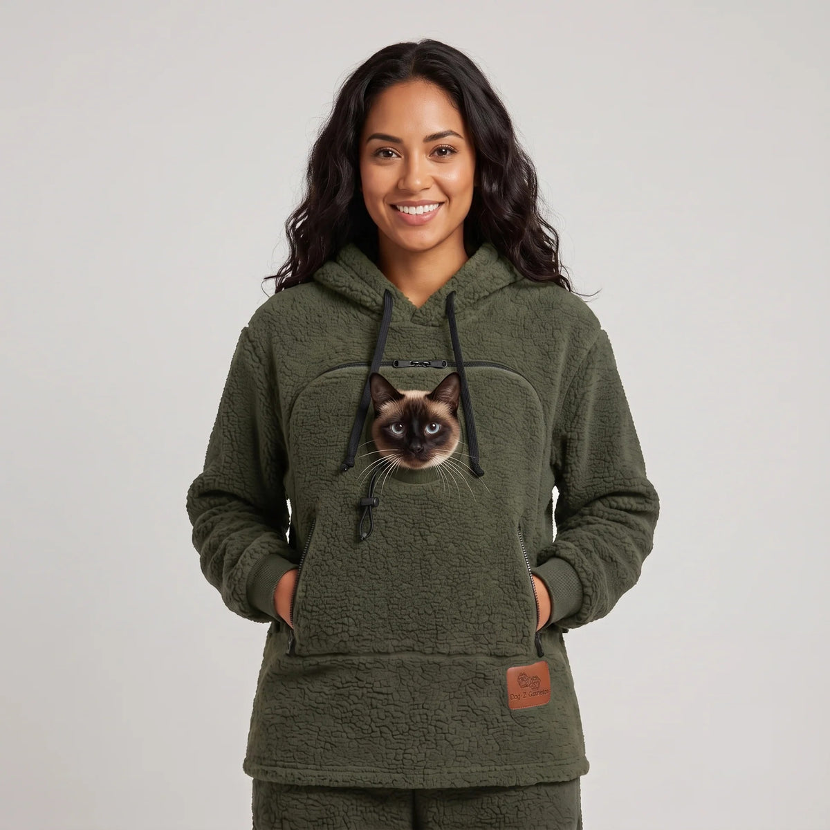 Woman wearing the moss green Dolgum Cozy Cat Hoodie with a Siamese cat in the front pouch
