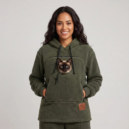 Woman wearing the moss green Dolgum Cozy Cat Hoodie with a Siamese cat in the front pouch