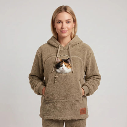 Woman wearing the beige Dolgum Cozy Cat Hoodie with a calico cat in the front pouch