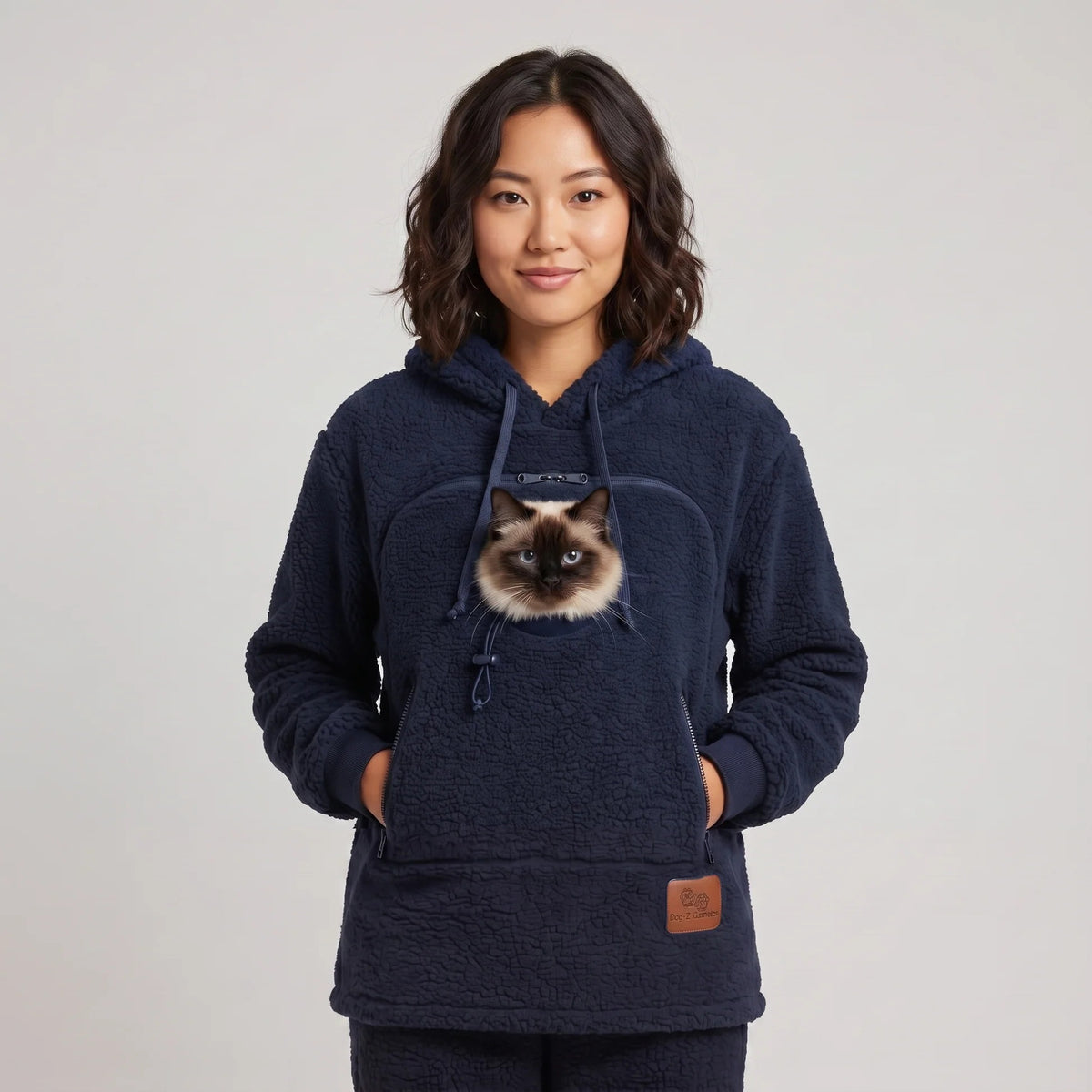 Woman wearing the navy blue Dolgum Cozy Cat Hoodie with a Siamese cat in the front pouch